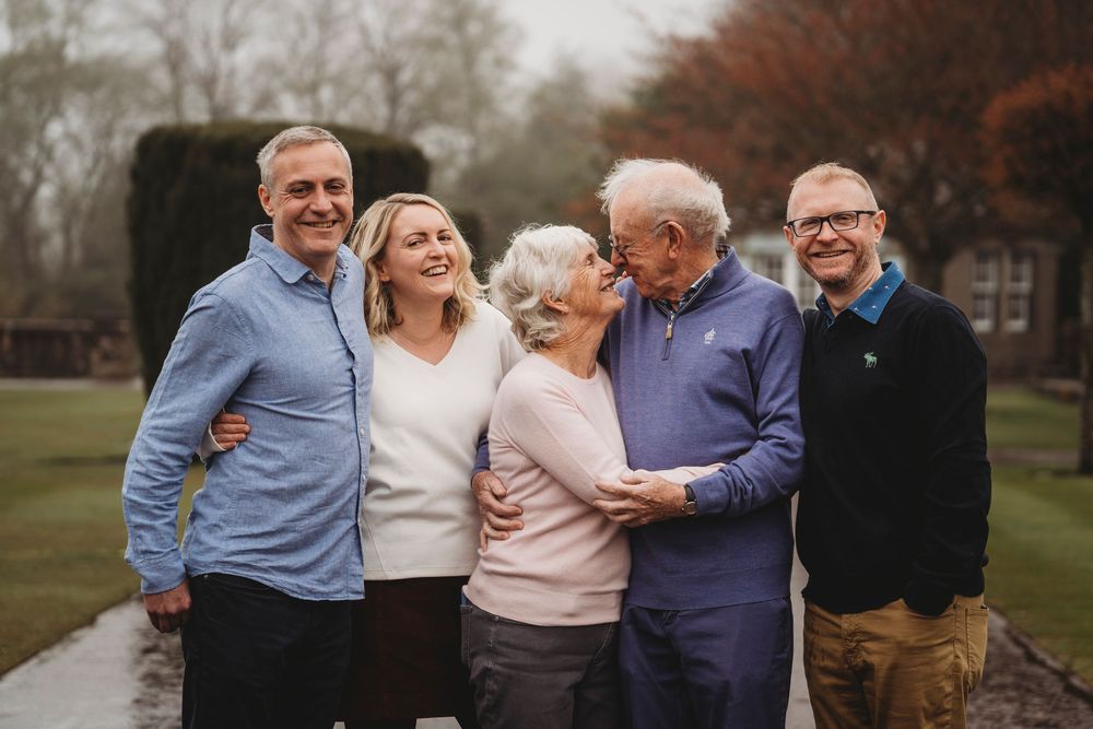 A group of people standing together outdoors on a misty autumn day wearing casual clothing.