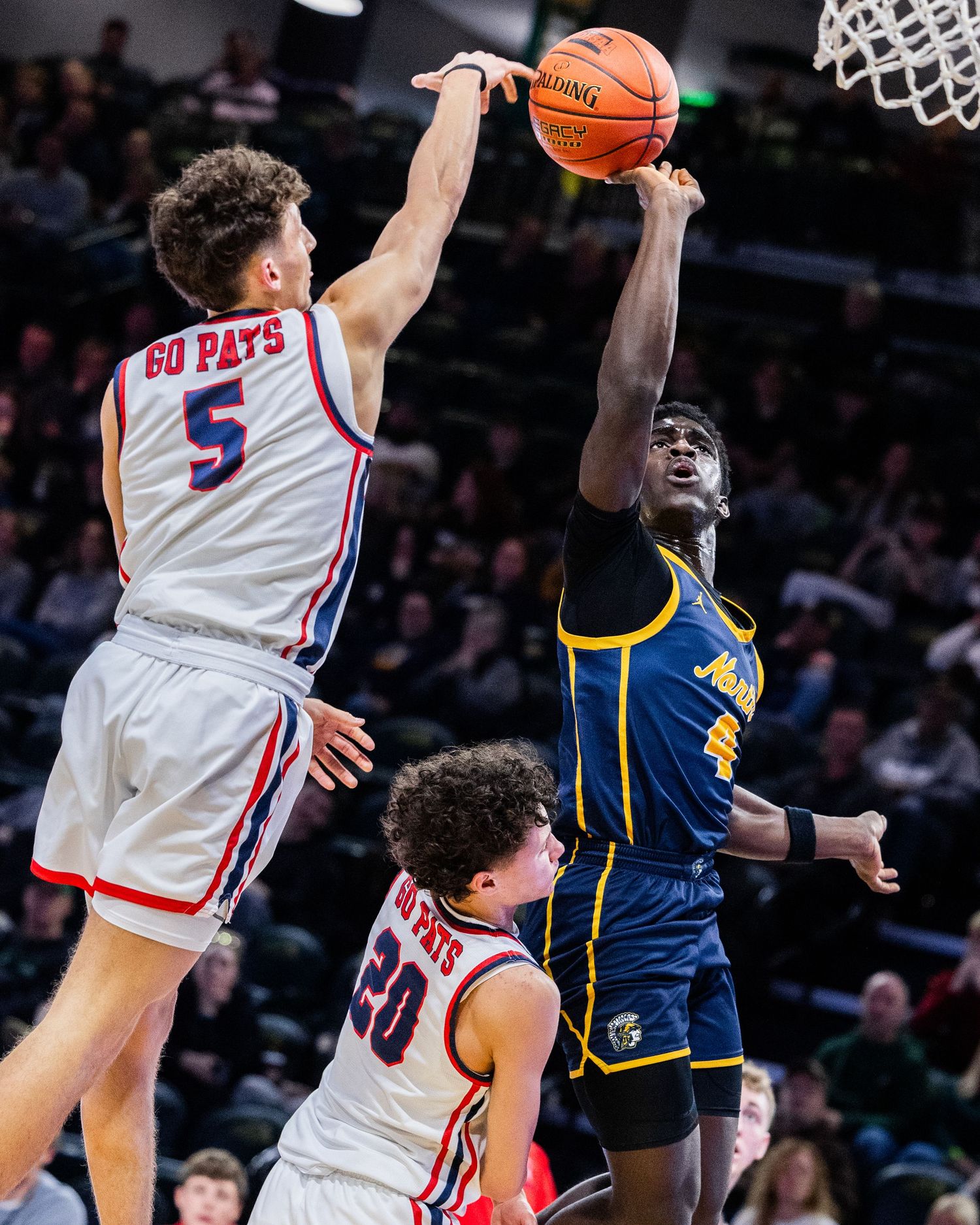 Basketball players leap high for a rebound during an intense college basketball game between DePaul and Marquette.