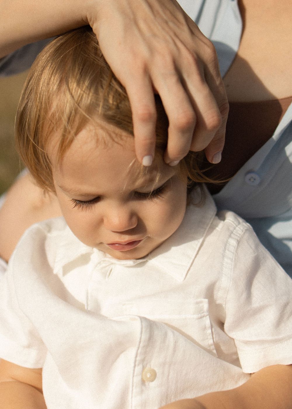 Close up of young child wearing white collared shirt in natural light.