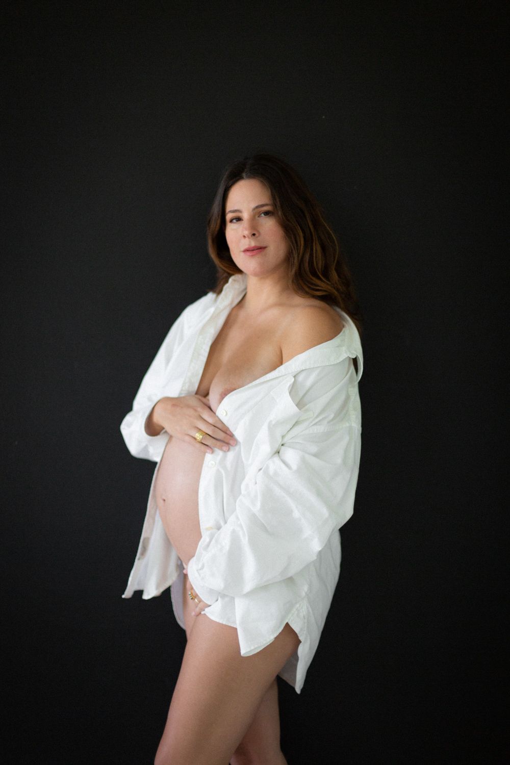 Artistic maternity photos with white shirt against dark background.