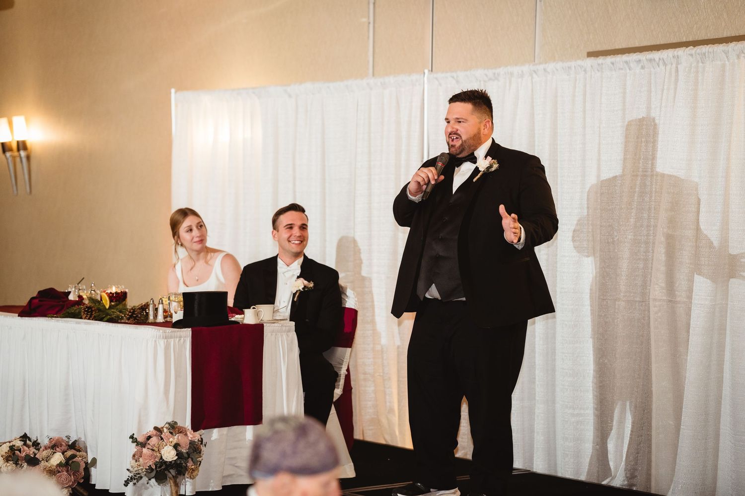 Wedding guests raise their glasses in a toast during an elegant indoor reception celebration.