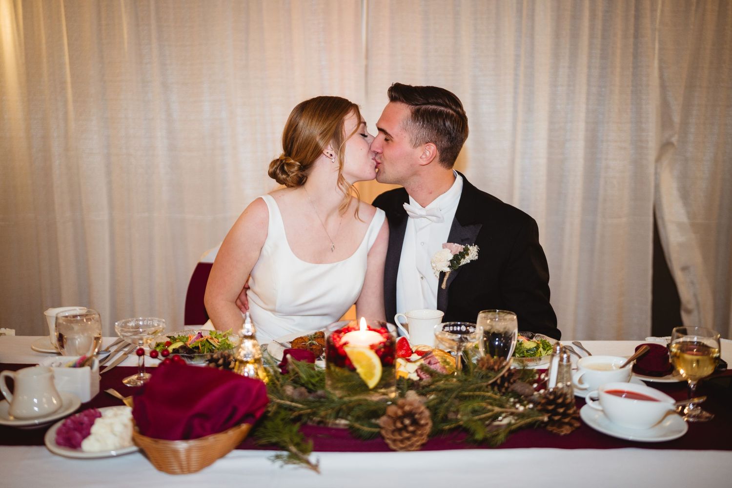 Elegant wedding reception table setting with white linens and floral centerpieces in a banquet hall.