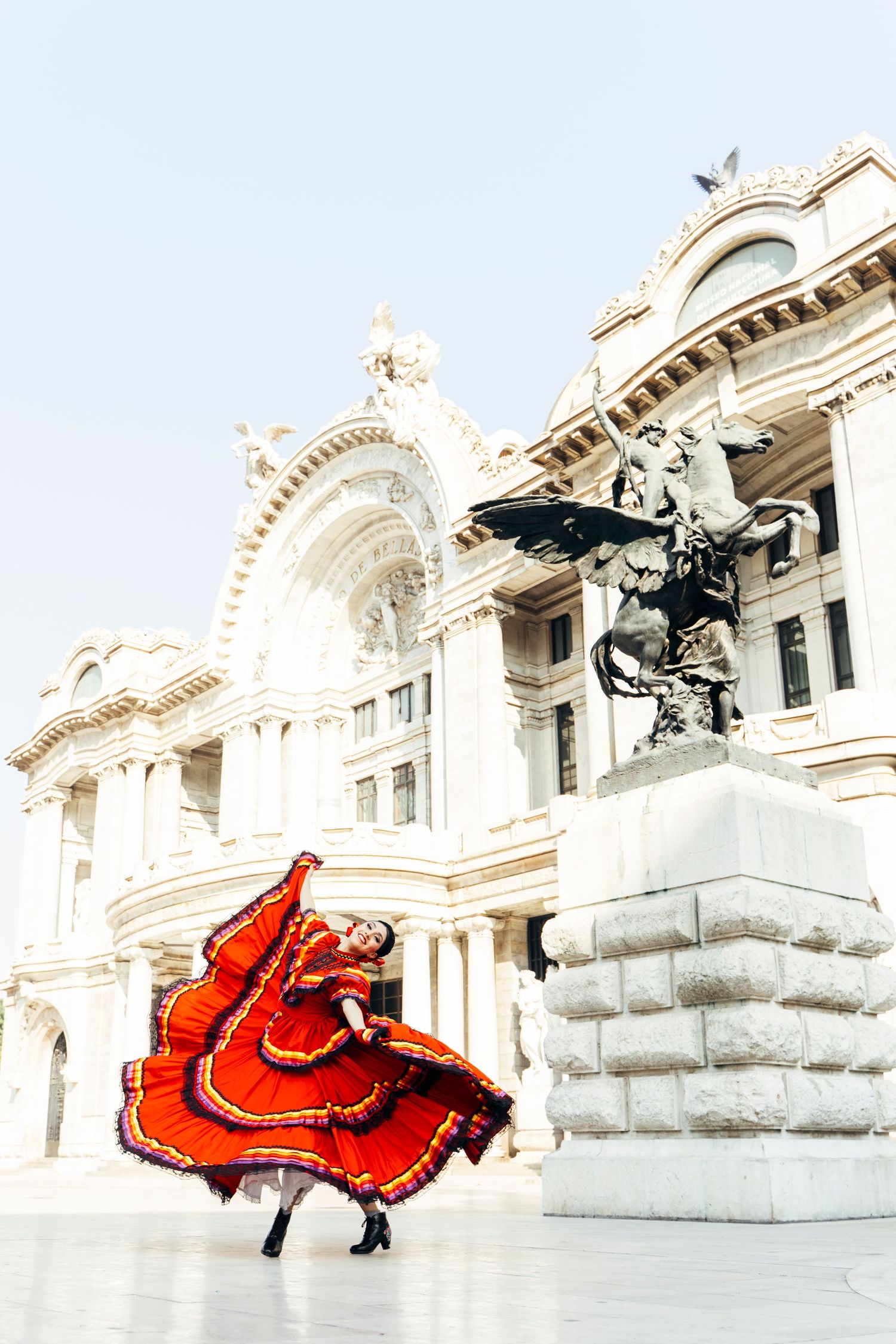Ballet Folklórico de México dancer performing expressive movement in front of Palacio de Bellas Artes