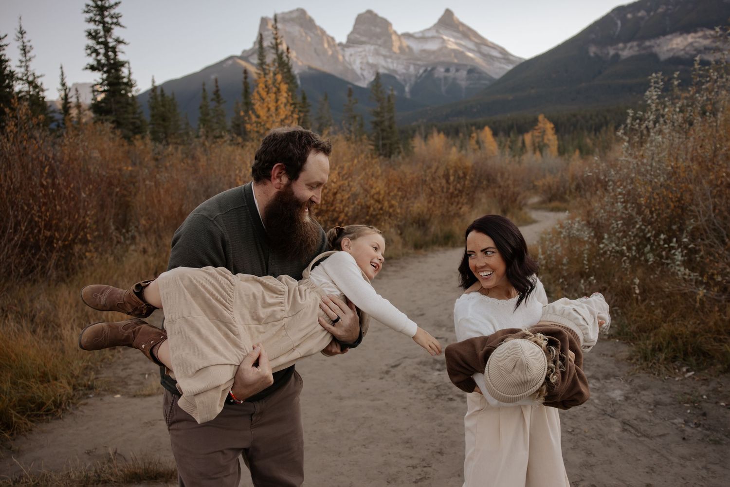 Family enjoying playful moments on mountain trail during golden hour.