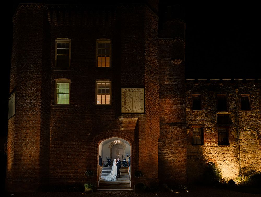 A row of illuminated windows in historic brick buildings at night creates a warm and mysterious atmosphere.
