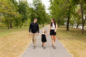 Three people walking together on a paved path through a park on a sunny summer day.