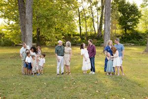 Group of people gathered outdoors in a park setting during a summer photo session with natural lighting.