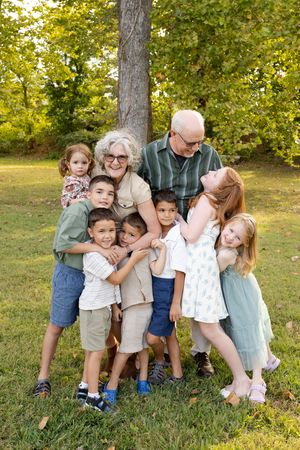 A playful family photo series showing group poses against a tree in a sunny outdoor setting.