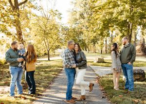 People walking and interacting along a tree-lined path during golden hour in a scenic outdoor setting.