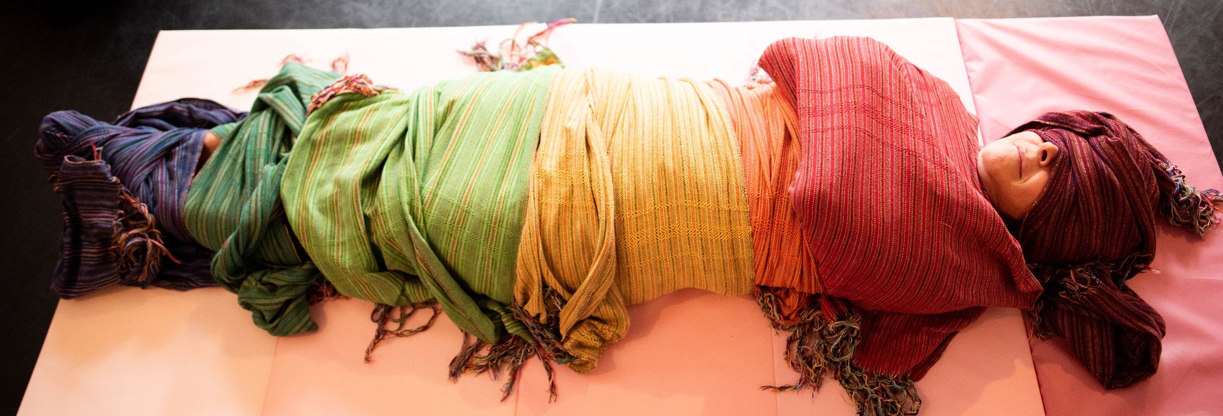 A colorful collection of yarn skeins in pink, green, orange and burgundy shades arranged in a row.