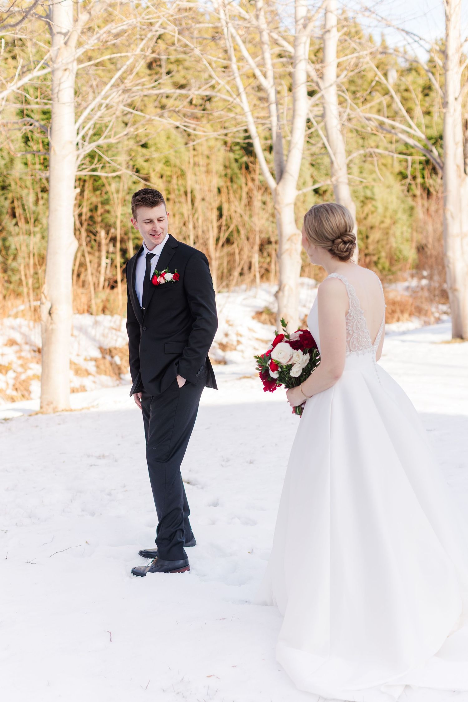 Romantic wedding couple shares intimate moments in a snow-covered woodland setting.