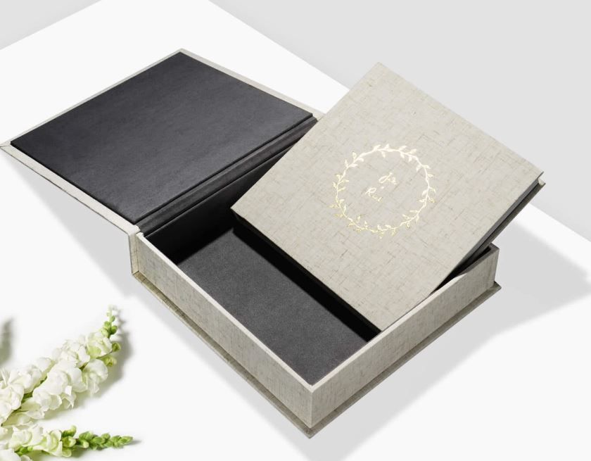 Elegant gray presentation box containing two premium photo albums with black and beige linen covers.