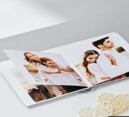 Open wedding photo album lying flat with multiple professional photographs displayed on white pages.