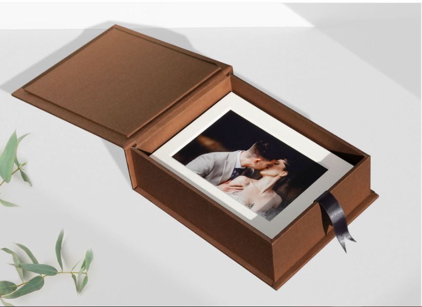 An elegant brown leather photo box with a hinged lid displays a black and white photograph inside.