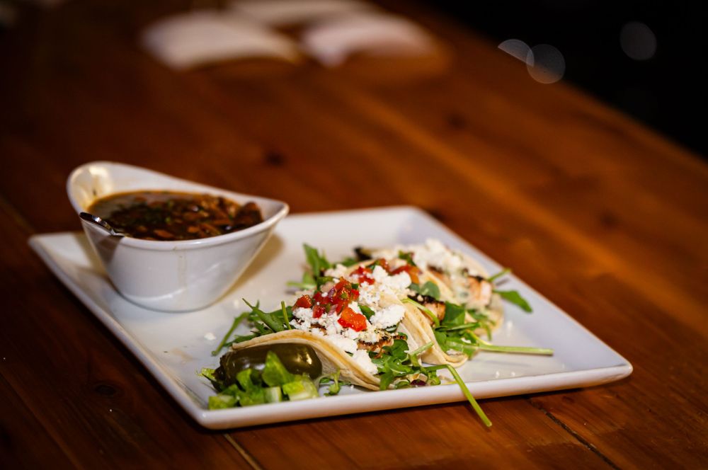 Artfully plated dishes on white plates against a wooden table surface.