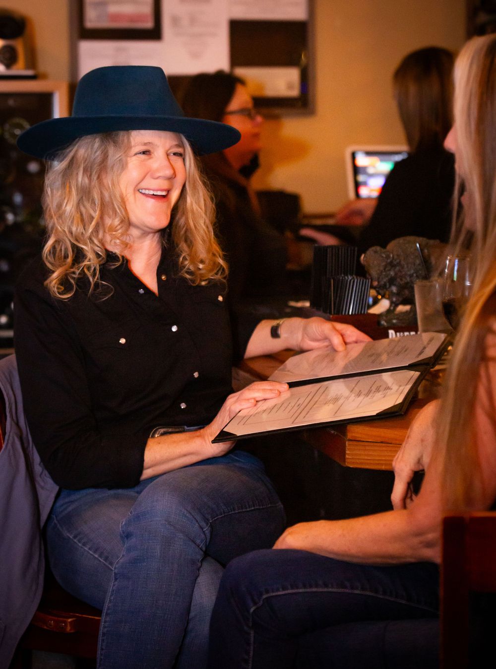 Casual restaurant scene with diners reviewing menus in warm lighting.