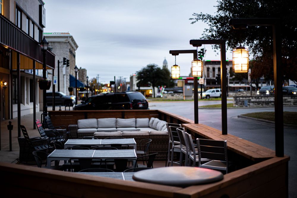 Exterior view of modern restaurant patio seating area at dusk.