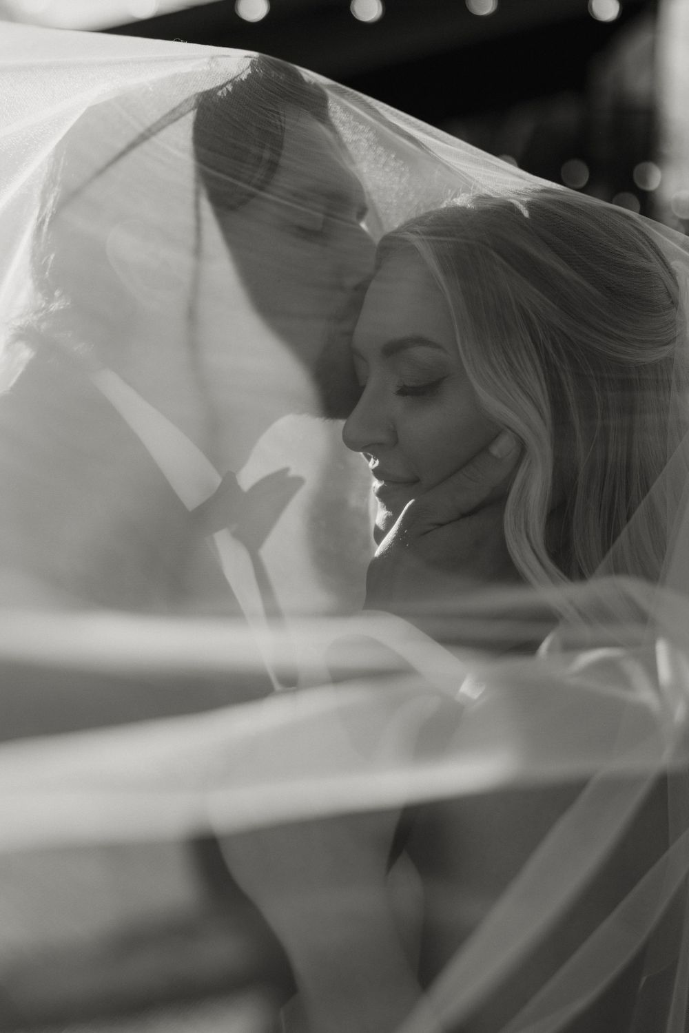 A romantic black and white wedding portrait sequence showing a couple under a flowing veil.