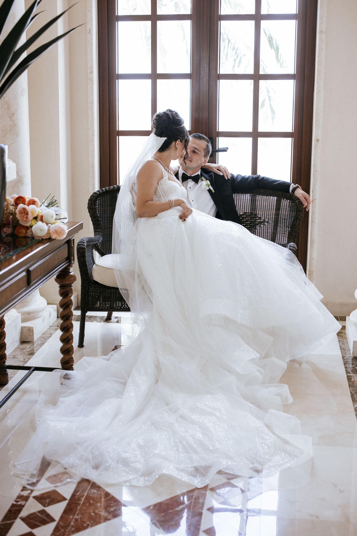 Bride and groom at Villa La Joya, sitting together with the bride on the groom's lap, gazing into each other's eyes, bathed in soft, natural