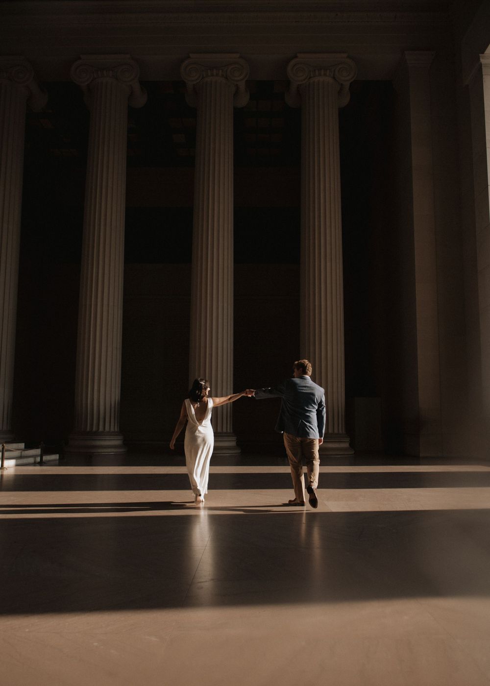 A couple dancing in a dramatic columned hall with moody lighting.
