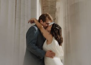 A passionate embrace between a couple wearing formal attire by white columns.