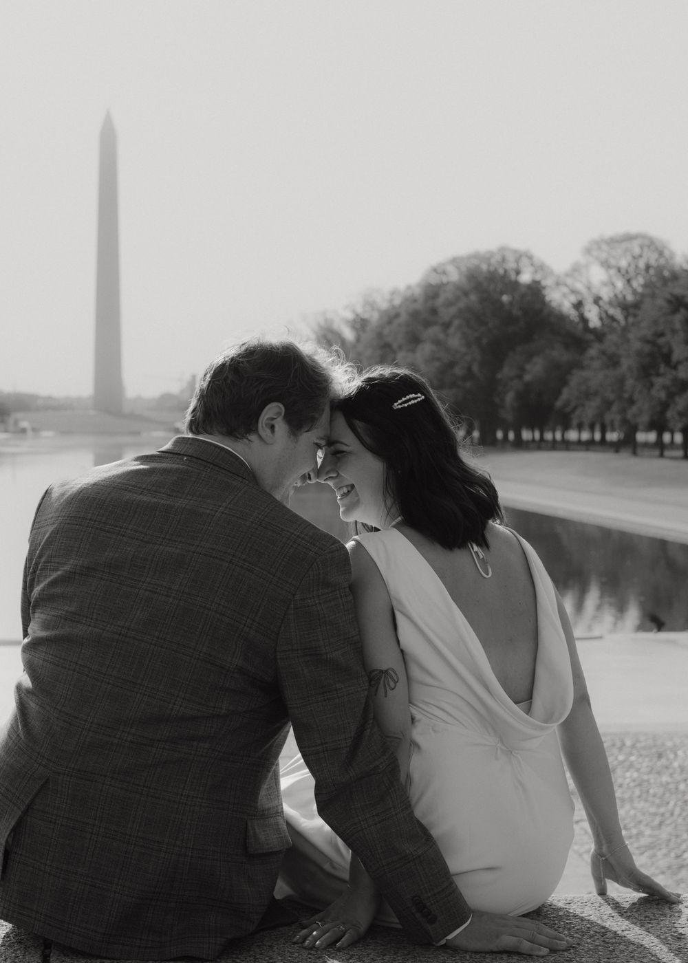 A couple shares an intimate moment by the Washington Monument reflecting pool.