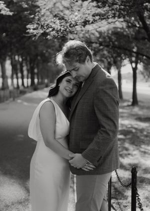 Black and white portrait of tender embrace on park pathway.