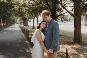 Candid moment of embrace captured on tree-lined pathway.