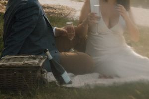 Detail shot of picnic setup with couple and wicker basket on blanket.