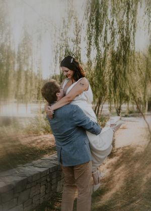 Joyful moment captured by willow tree as couple shares playful lift.