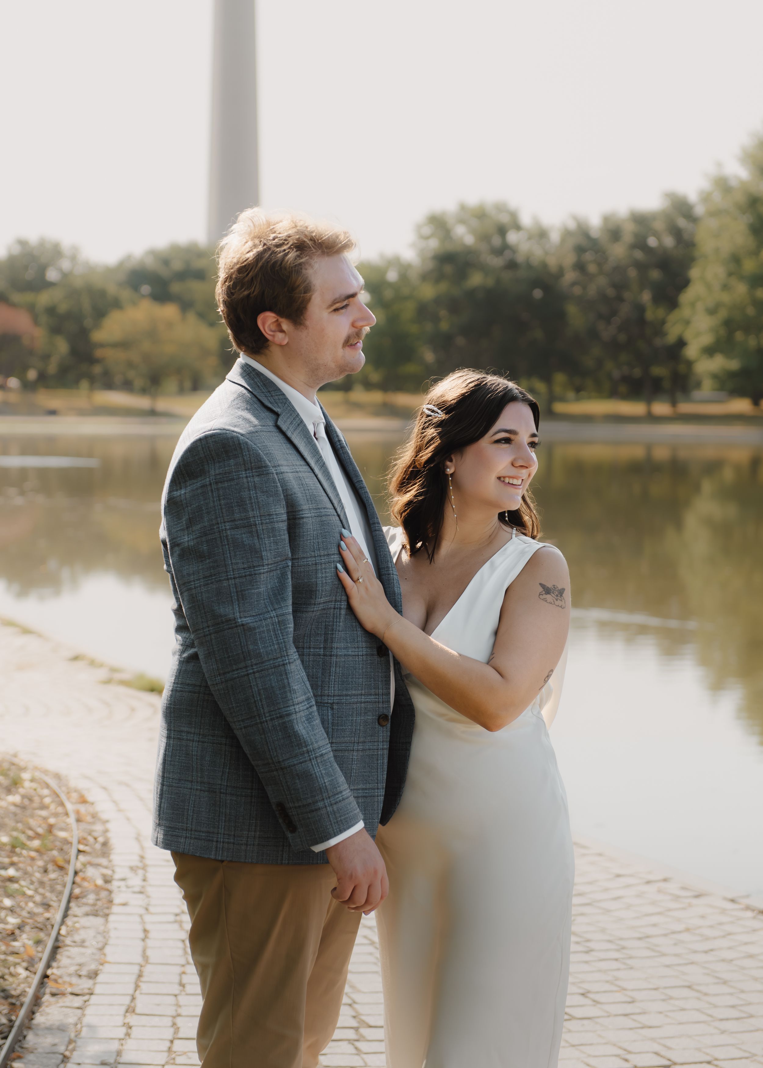 Loving couple embraces near Washington Monument on autumn day.