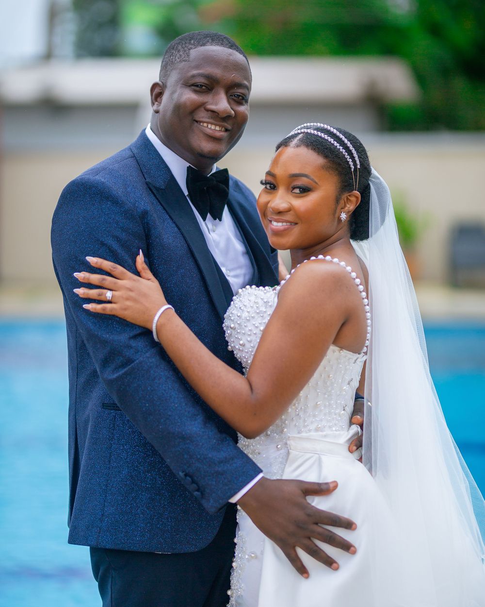 Elegant outdoor wedding portrait by a pool with classic formal attire.