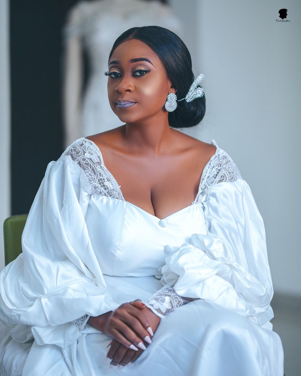 A bridal portrait featuring elegant makeup and a white lace robe with dramatic puff sleeves.