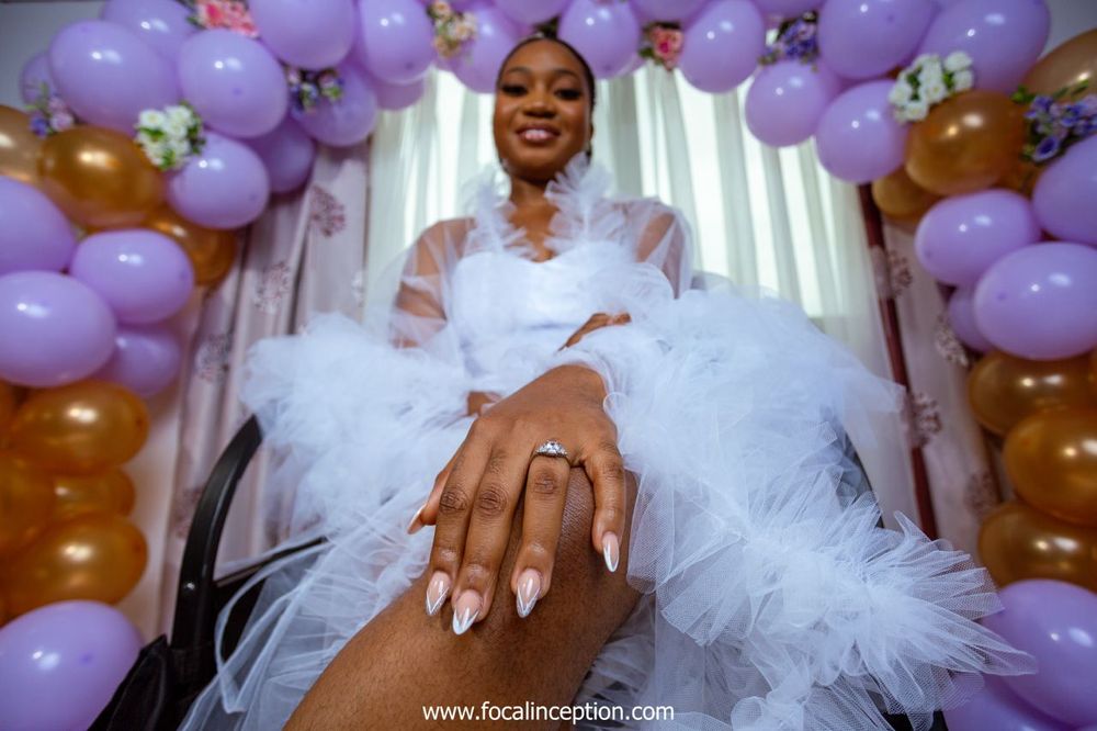 A joyful bridal photo taken from below featuring purple and gold balloon decor.