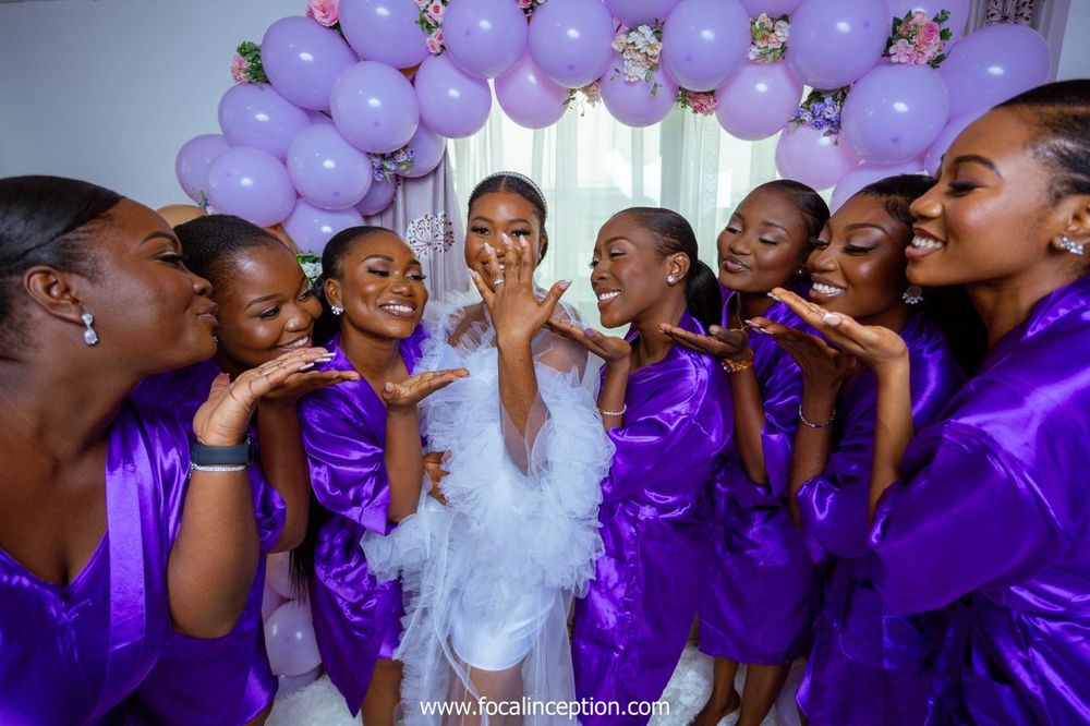 Wedding party scene with bridesmaids in purple satin robes posing playfully together.