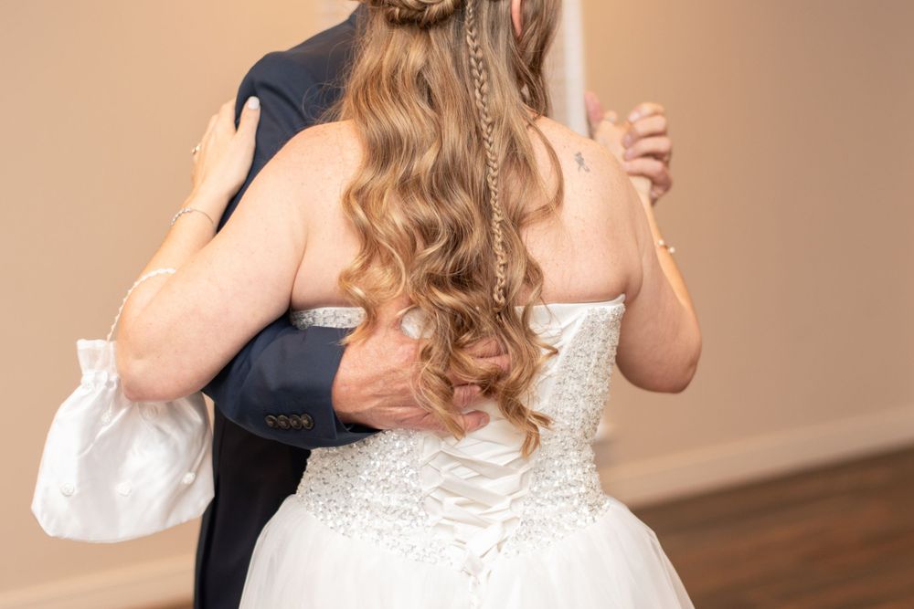 A close-up view of a bride with long curled hair dancing in her white lace wedding dress.