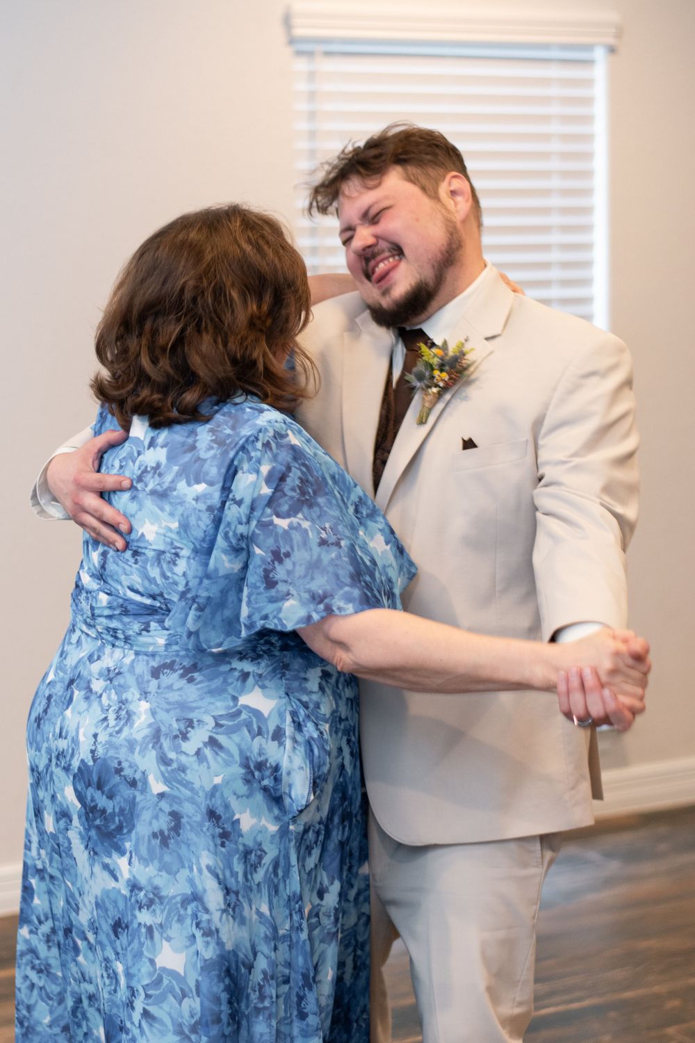 A heartwarming dance at a wedding between someone in a blue floral dress and another person in a light beige suit.