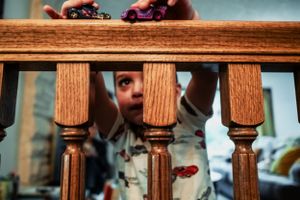 Creative shot through wooden banister spindles showing someone peering through the decorative wooden railing.