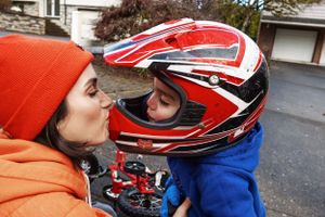 A tender moment as two riders share a kiss while one wears a red and white motorcycle helmet.
