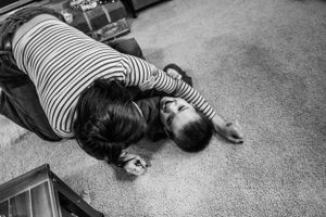 A person in striped shirt lies on carpet floor in black and white photograph.