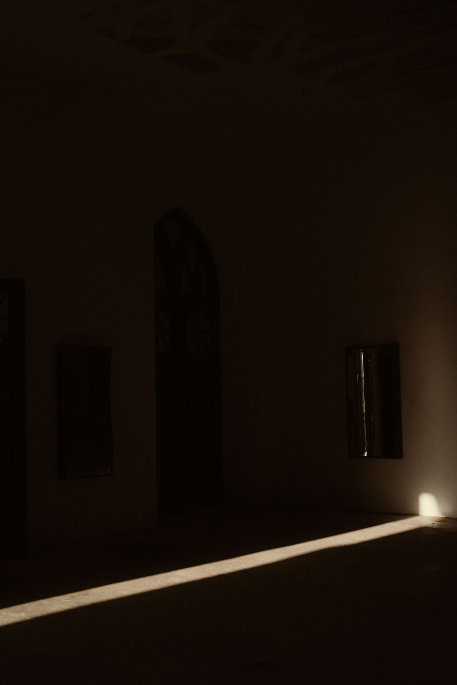 Beam of light streaming across dark room creating dramatic line on floor.