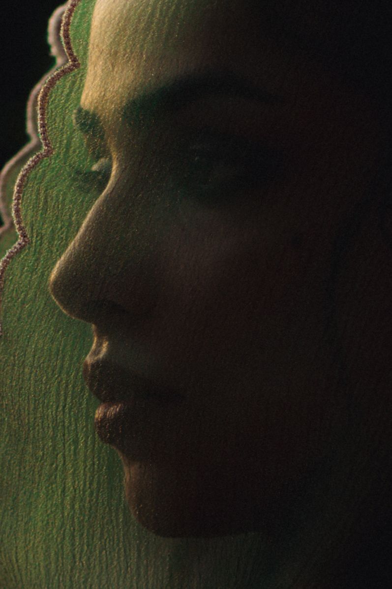 Silhouetted profile against green textured background in dramatic lighting.