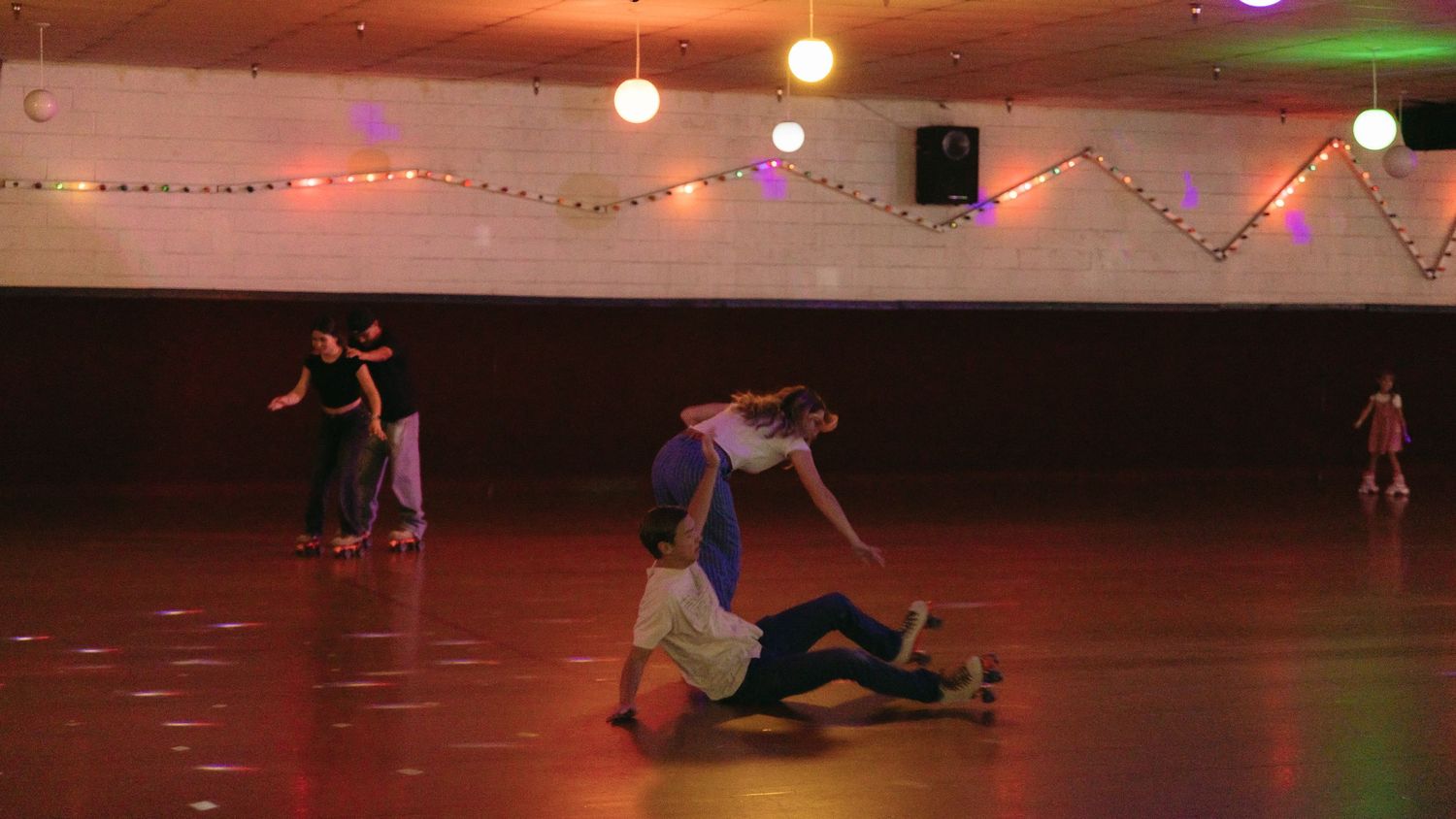 Dancers perform on a dark stage illuminated by colorful string lights and spotlights during a dance performance.