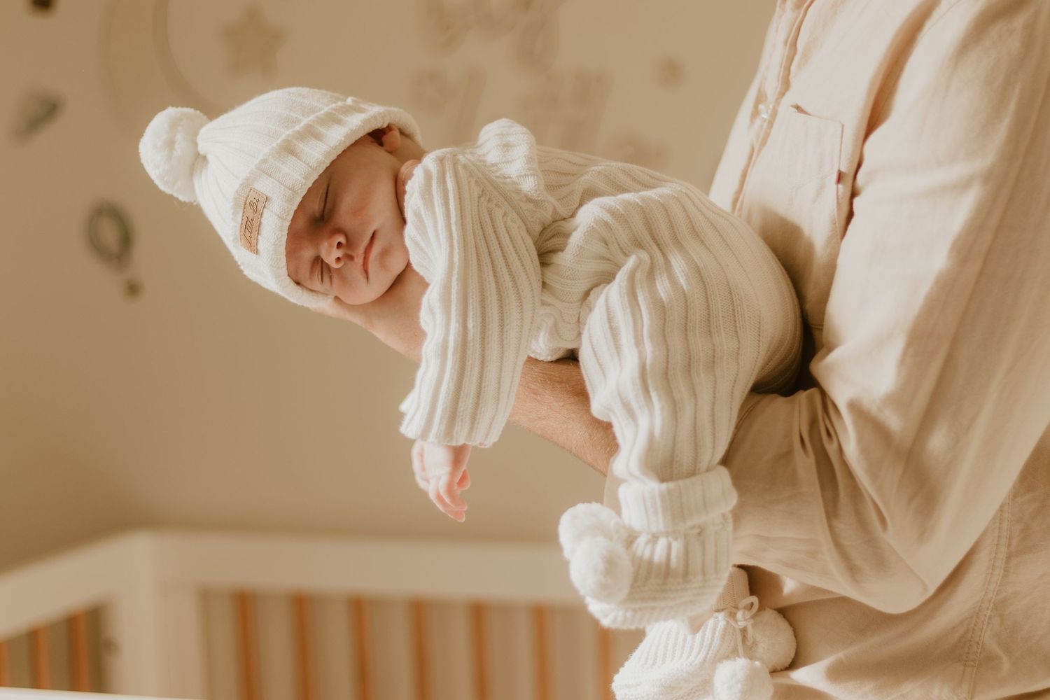 newborn baby laying in father's arms