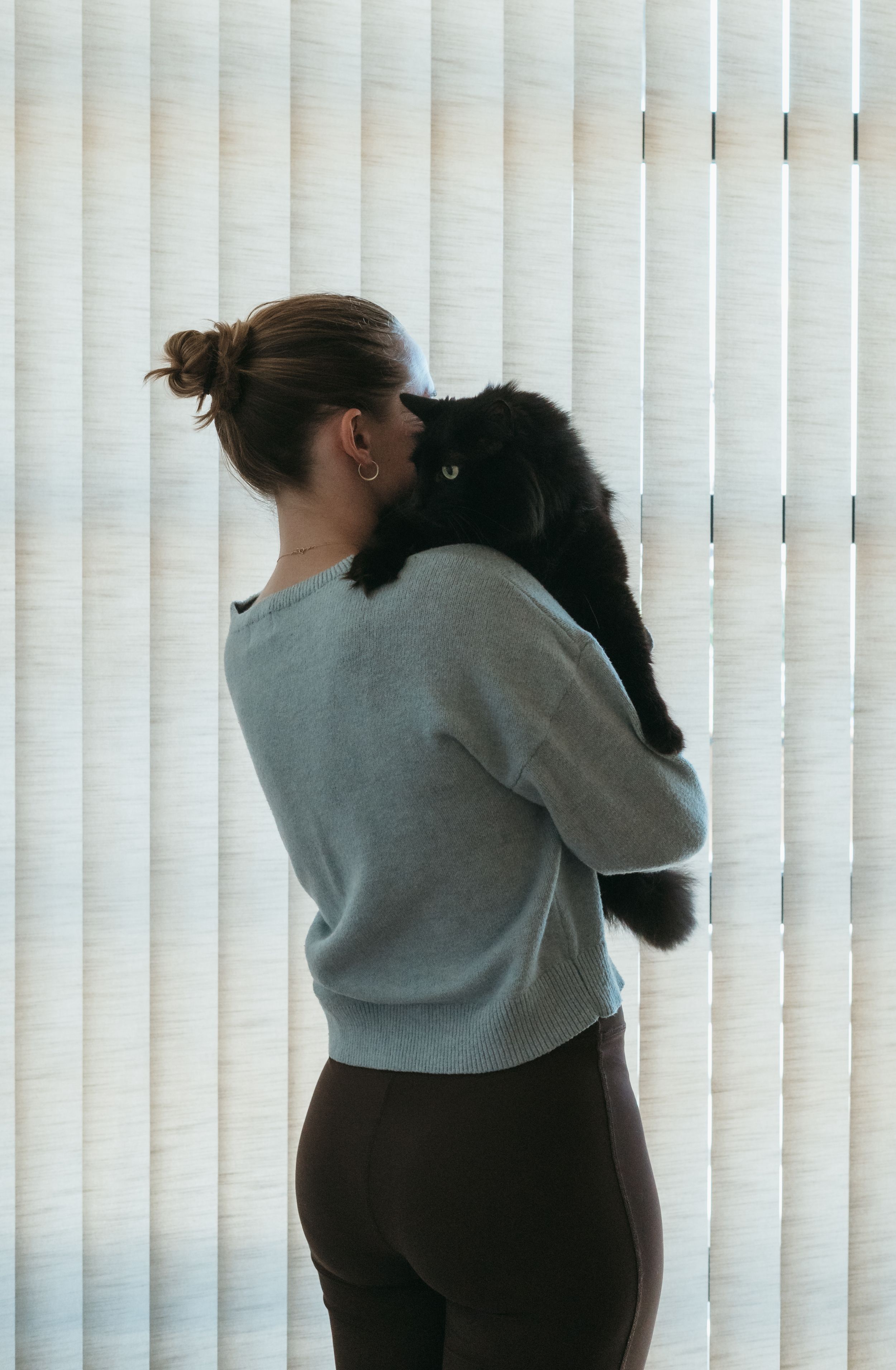 A hugging sequence of three progressive images showing a growing embrace against a window with vertical blinds.