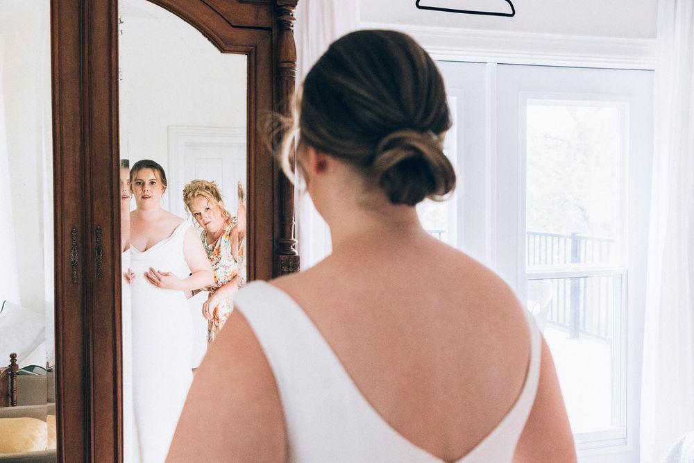 Reflection of wedding preparation moment in ornate mirror frame.