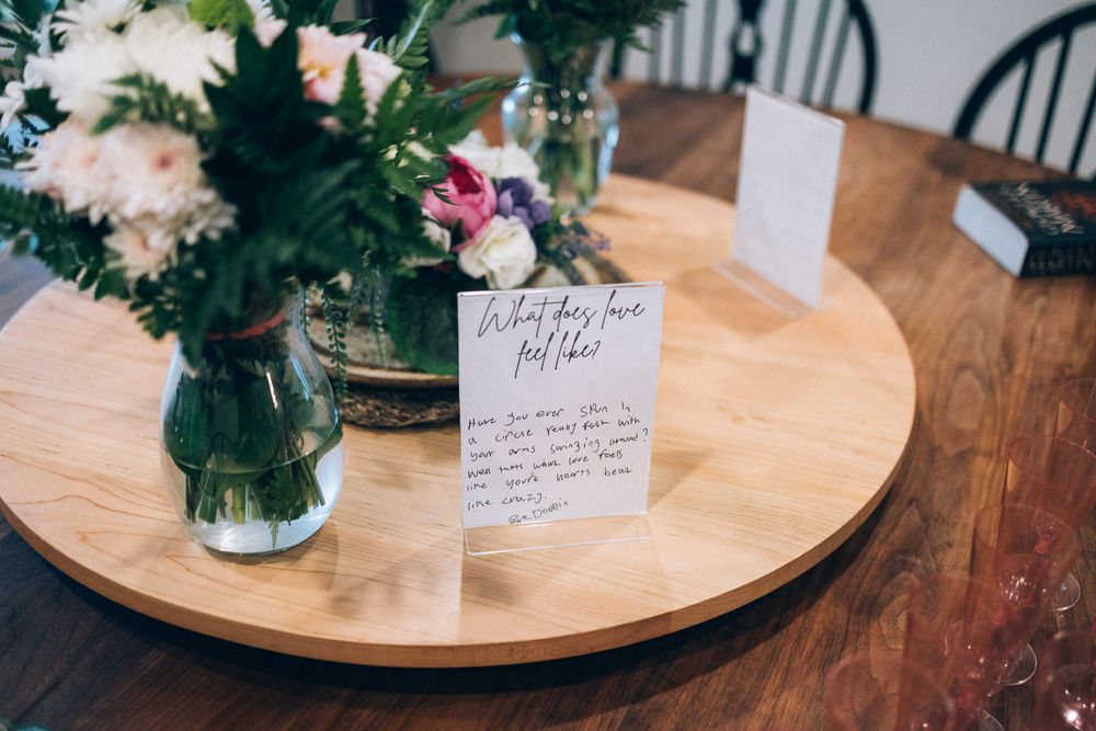 Wedding reception table with floral centerpiece and handwritten note card.