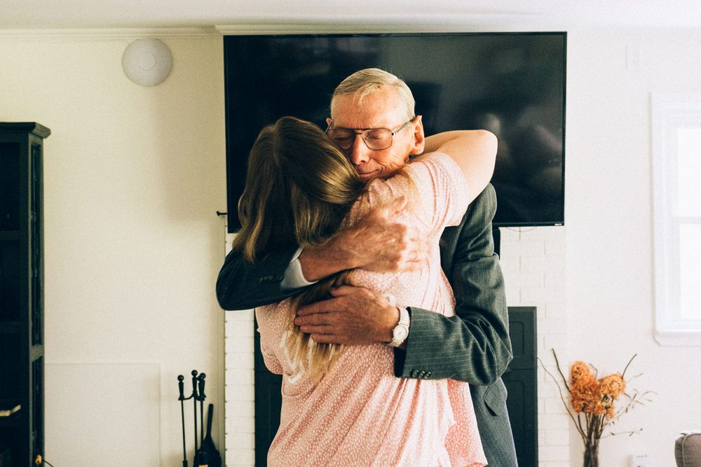 Emotional embrace captured during wedding celebration with TV mounted on wall in background.