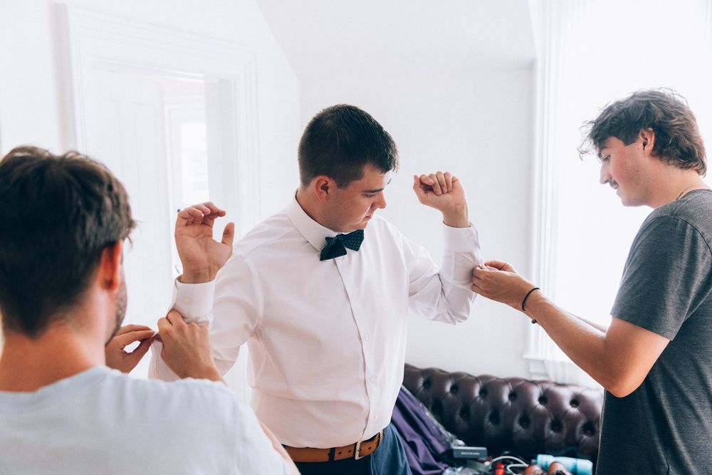 Three people helping with bow tie adjustments before formal event.