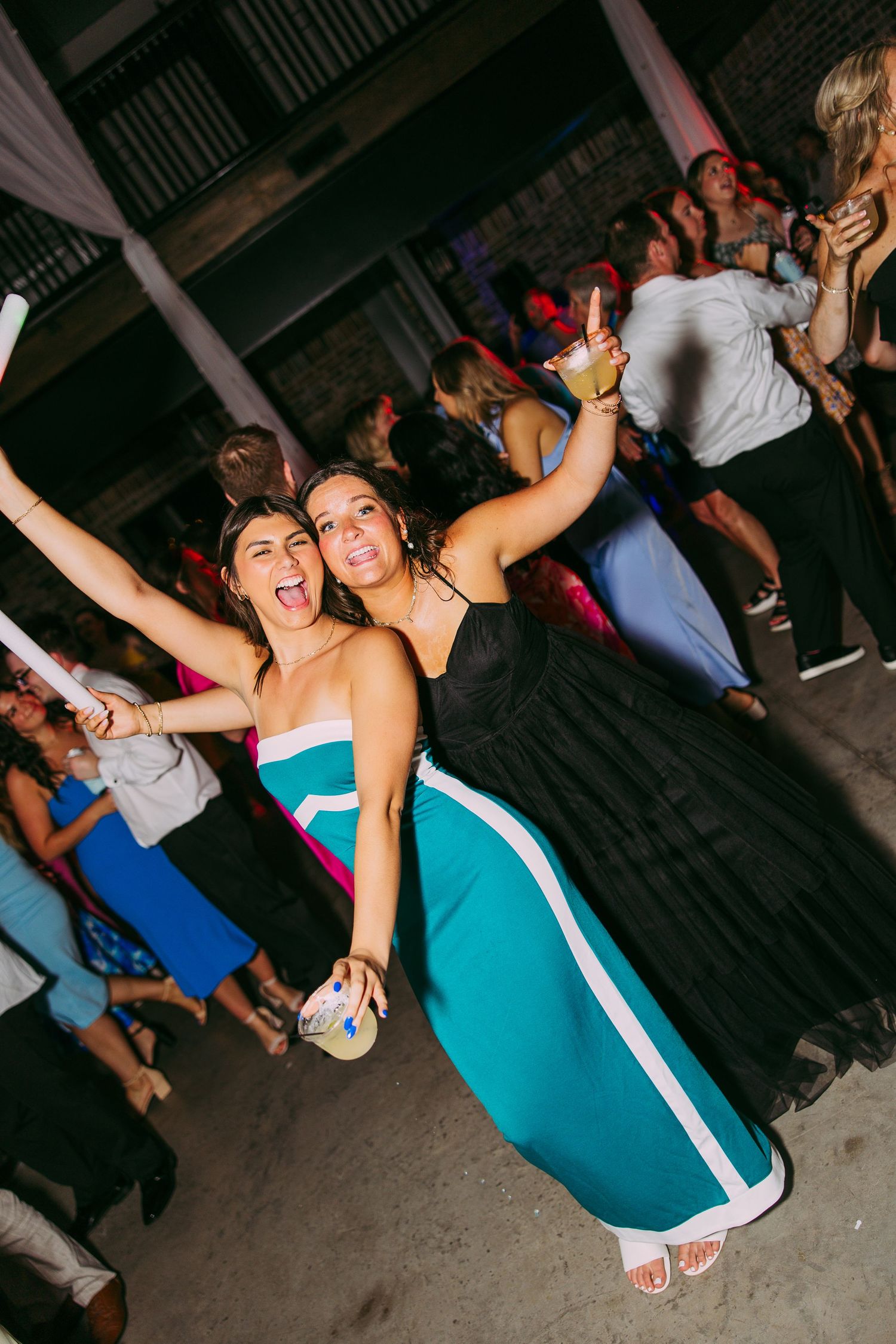 Guests dancing and celebrating energetically at a party with one wearing a bright turquoise dress.